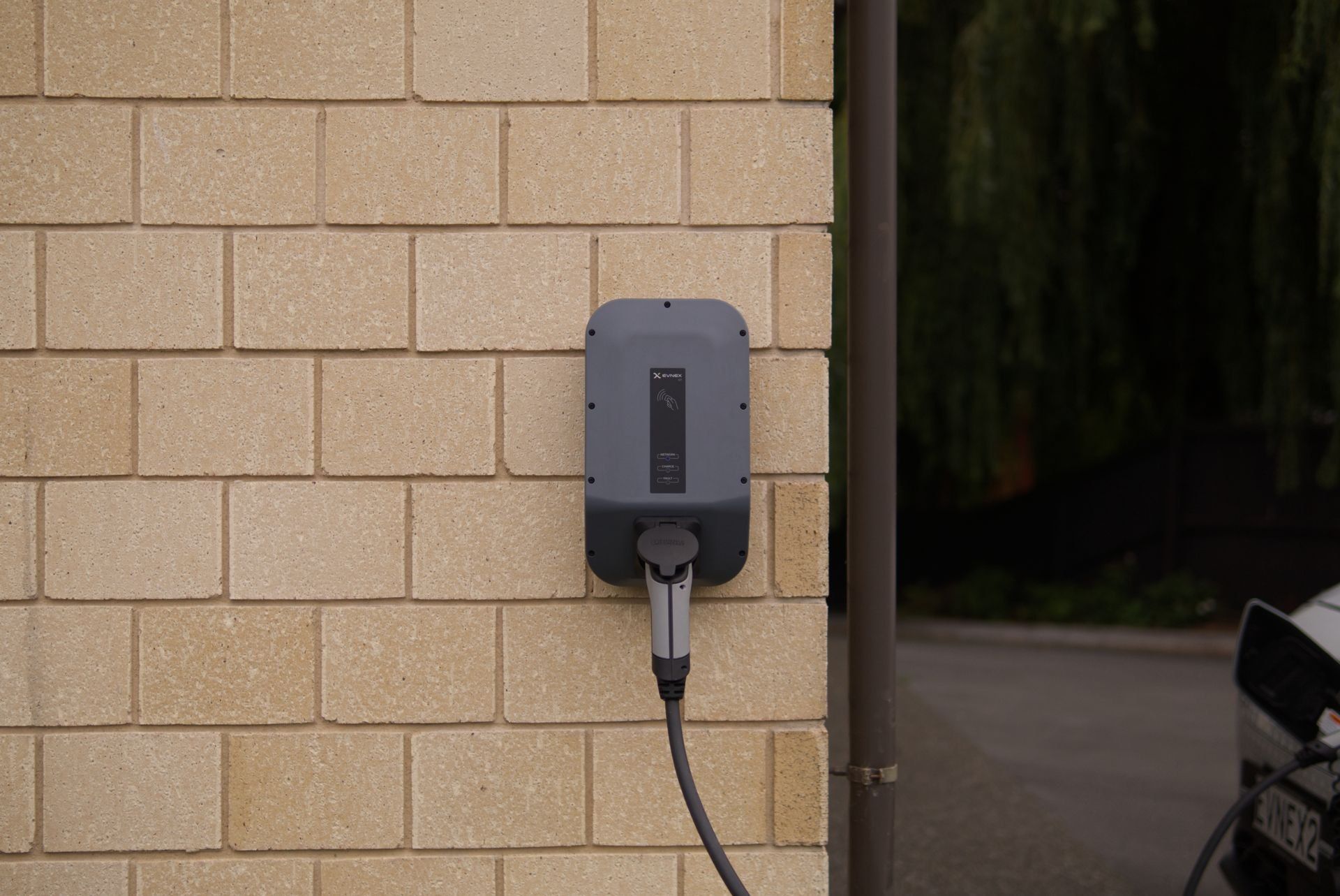 Wallbox an einer Hauswand, das Ladekabel ist eingesteckt